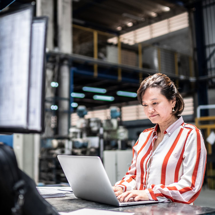Woman typing on a laptop at a desk.